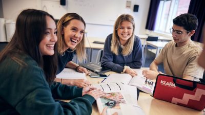 Elever sitter runt ett bord och arbetar med ett grupparbete
